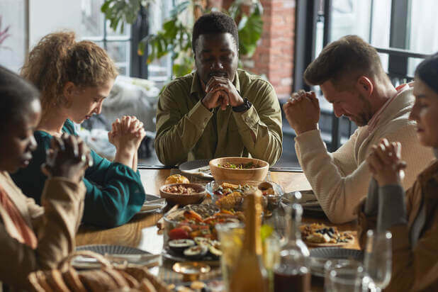 Group of People Praying at the dinner table.